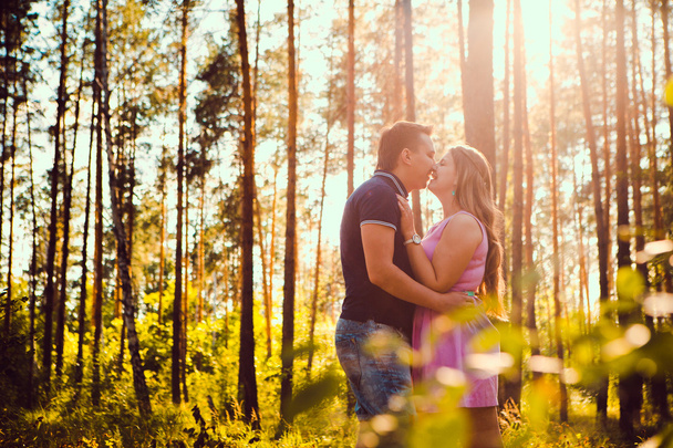 Romantic young couple kissing on background summer forest - Foto, afbeelding