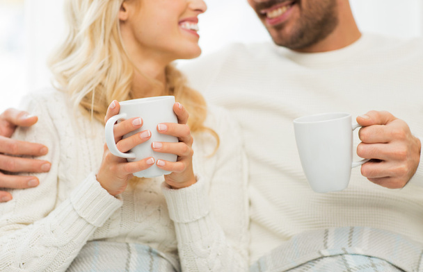 close up of happy couple with tea cups at home - Foto, imagen