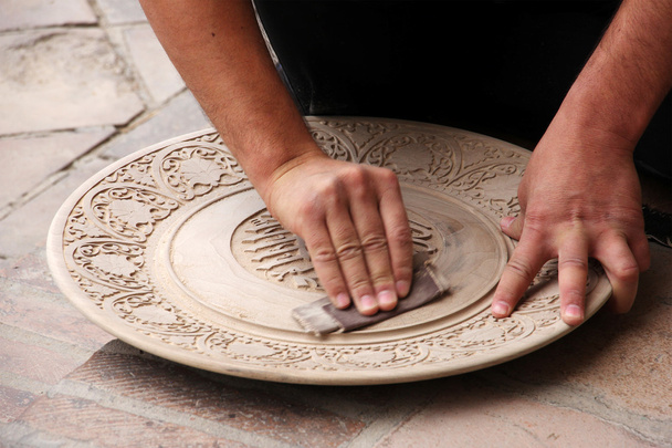 man polishes round a wooden plate with sandpaper - Φωτογραφία, εικόνα