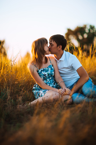 Romantic couple standing and kissing on background summer meadow sunset - Foto, Bild