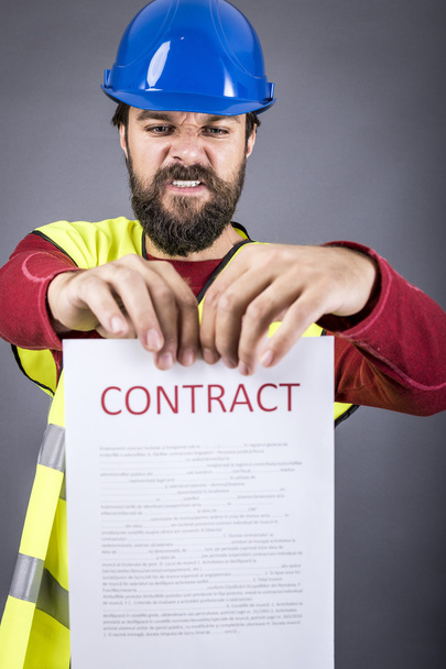 Frustrated young engineer with hardhat and reflective vest  tear - Foto, Bild