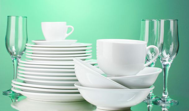 Clean plates, cups and glasses on green background - Φωτογραφία, εικόνα