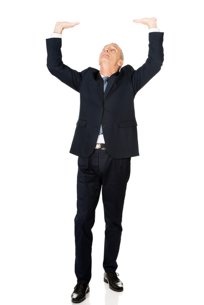 Full length businessman pushing invisible ceiling - Foto, immagini