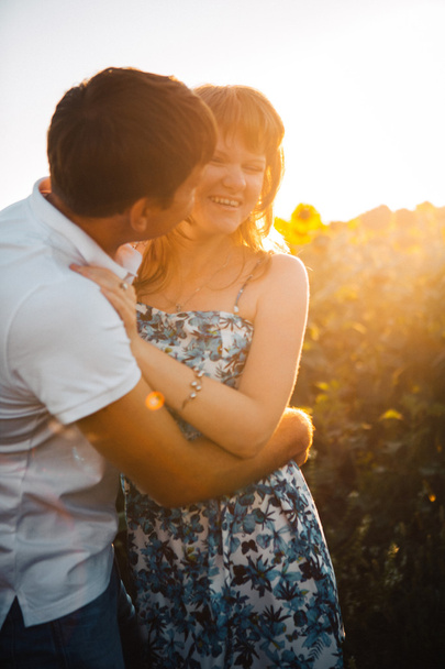 Romantikus pár állt, és a háttér nyáron a területen napraforgó sunset csók - Fotó, kép