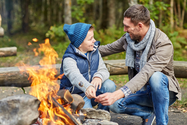 father and son roasting marshmallow over campfire - Fotoğraf, Görsel