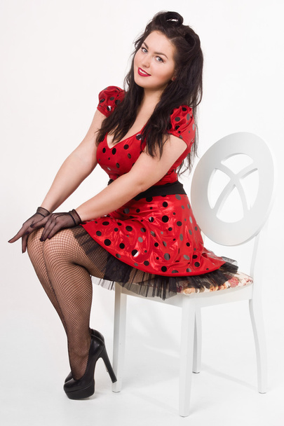 Attractive pin-up girl sitting on a chair - Фото, изображение