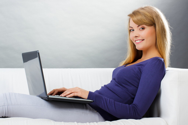 Szczęśliwa kobieta za pomocą laptopa siedząc na kanapie, nowoczesnych technologii - Zdjęcie, obraz
