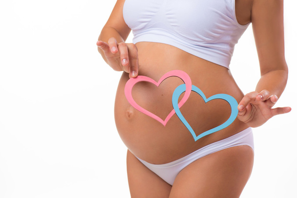 Happy pregnancy. Smiling pregnant woman holding a plate with two hearts. Mother Love. Twins, girl, boy. - Foto, afbeelding