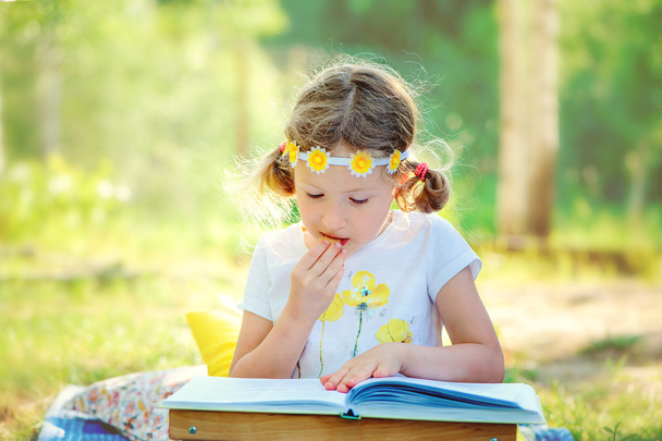 little girl reading book in garden - Photo, Image