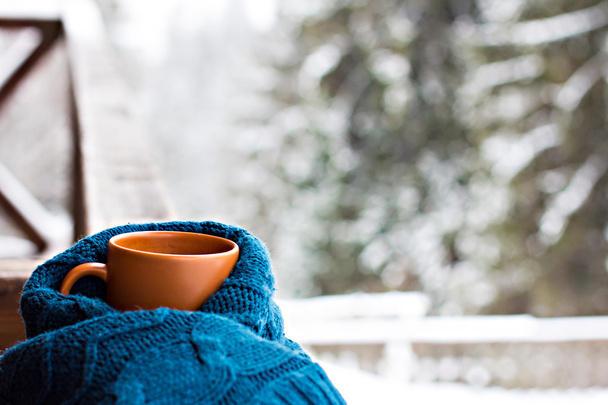 eine Tasse mit einem heißen Getränk vor dem Hintergrund des Winterwaldes - Foto, Bild