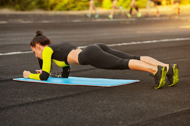 Femme athlétique mince faisant de l'exercice de planche dans le stade, entraînement de fille sportive, extérieur
 - Photo, image