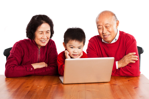 Senior Asian grandparents using computer with their grandson - Фото, изображение