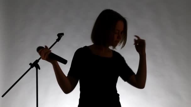 Silhouet van een meisje met microphne zingen - Video