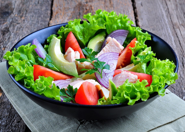 gesunder Salat aus Avocado, Tomaten, Thunfisch aus der Dose, Zwiebeln und Salat mit Parmesan, Petersilie und Olivenöl - Foto, Bild