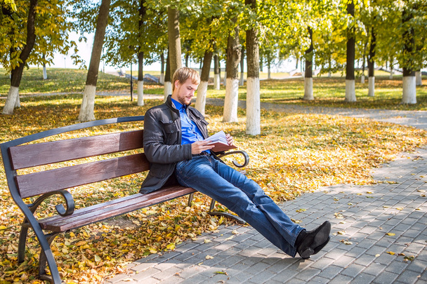 Ein Mann sitzt mit dem Buch im Stadtpark - Foto, Bild