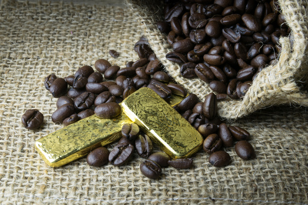Κόκκους καφέ και του χρυσού σε λινάτσα τσάντα σε ξύλινα backgro - Φωτογραφία, εικόνα