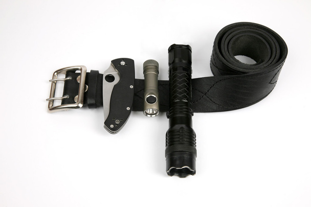 folding knife, a flashlight and a Taser on a black leather strap - Foto, imagen