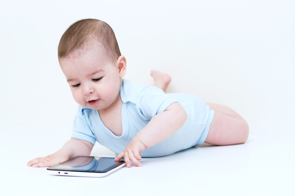 Happy baby with tablet lying on white floor - 写真・画像