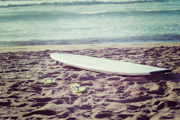 tabla de surf y chanclas en la arena
 - Foto, imagen