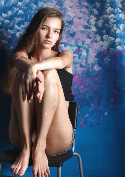 Young woman sitting near painting wall - 写真・画像