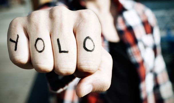 junger Mann mit dem Wort yolo in den Fingerknöcheln - Foto, Bild