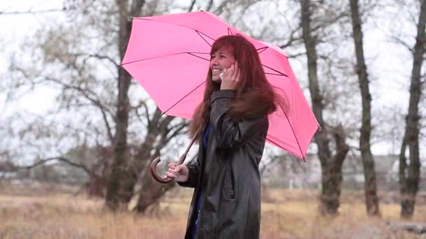 Žena hovoří s růžovým deštníkem telefonicky - Záběry, video