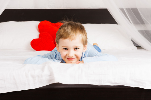 Smiling boy laying on bed - 写真・画像