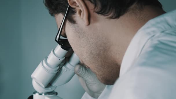 Médico joven mirando a través del microscopio
 - Imágenes, Vídeo