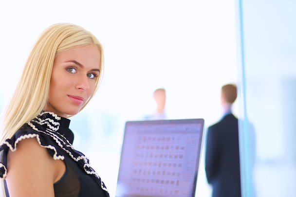 Young businesswoman holding a laptop, standing on office - Foto, afbeelding