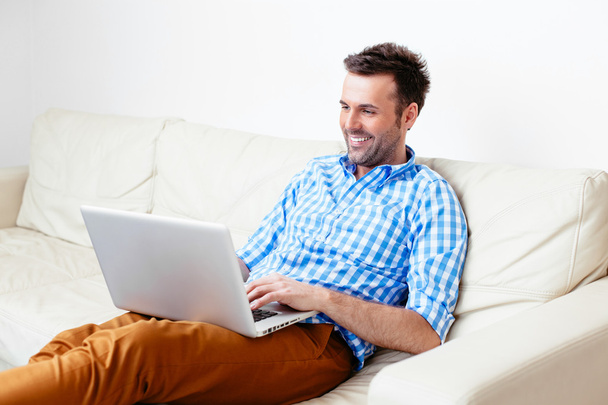 glücklich schöner Mann sitzt auf einem Sofa - Foto, Bild