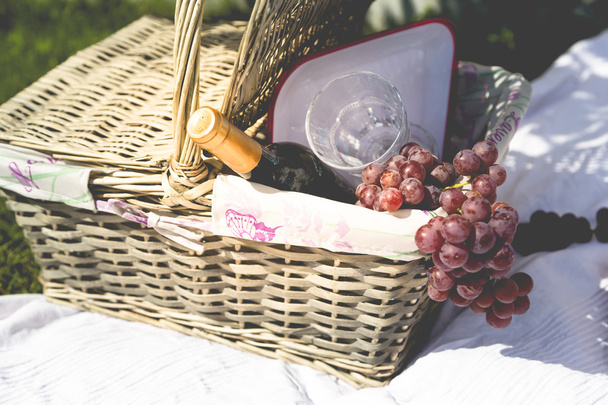 Picnic basket, blanket, wine glass and grapes - 写真・画像