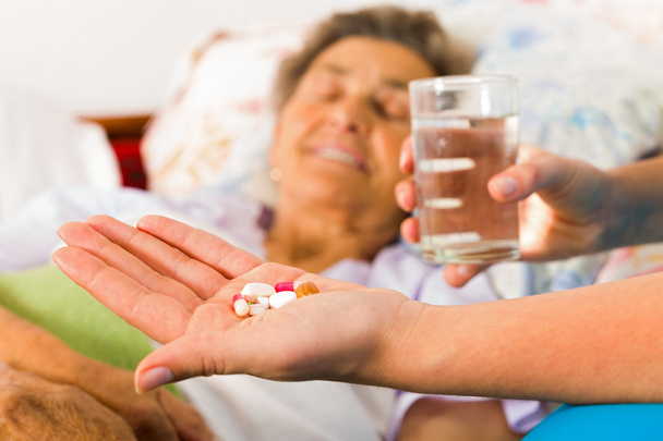 Elderly woman taking pills with water - Zdjęcie, obraz