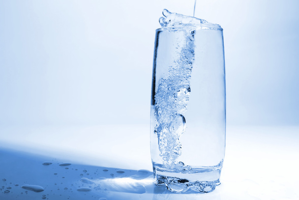 νερό ρίχνει σε διαφανές ποτήρι με φυσαλίδες αέρα - Φωτογραφία, εικόνα