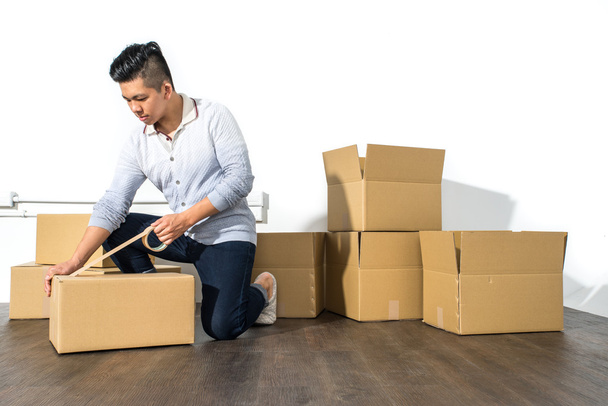 Young asian man moving house Packing cardboard using adhesive - Valokuva, kuva