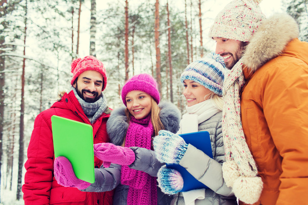 smiling friends with tablet pc in winter forest - Foto, Bild