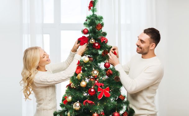 happy couple decorating christmas tree at home - Foto, afbeelding