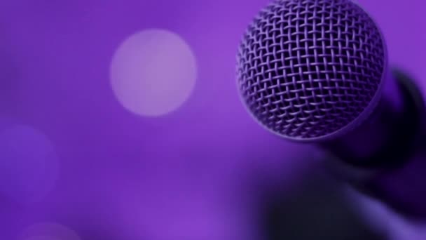 Primer plano del micrófono en el escenario con iluminación en tonos púrpura
 - Metraje, vídeo