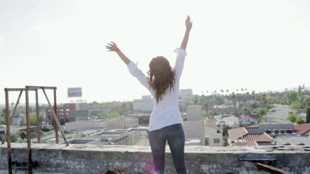 Vrouw op een dak met haar armen wijd open kijken weergave - Video