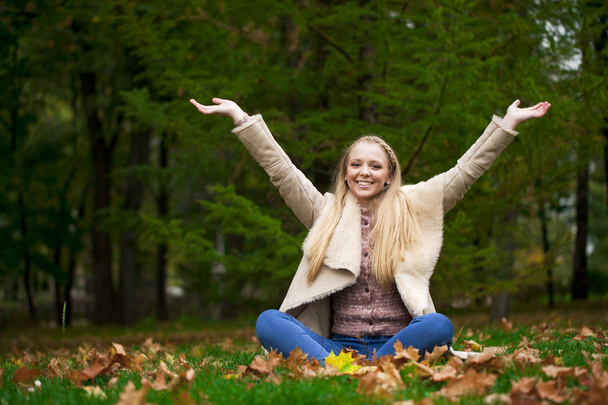 秋の公園で歩く若い幸せなブロンドの女性 - 写真・画像