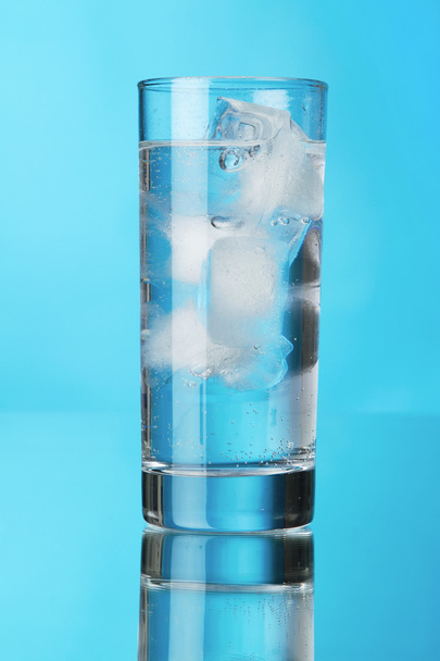 Glass of ice water on blue background - 写真・画像