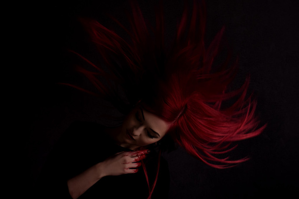 Donkere portret van een mooi meisje met de ontwikkeling lang rood haar en vingers in bloed - Foto, afbeelding