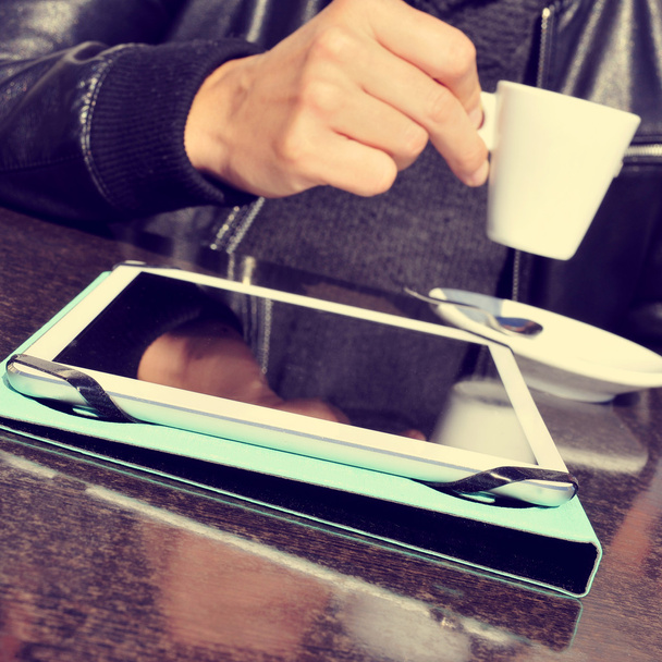 ember, egy csésze kávé és egy tabletta, egy kávézó teraszán - Fotó, kép