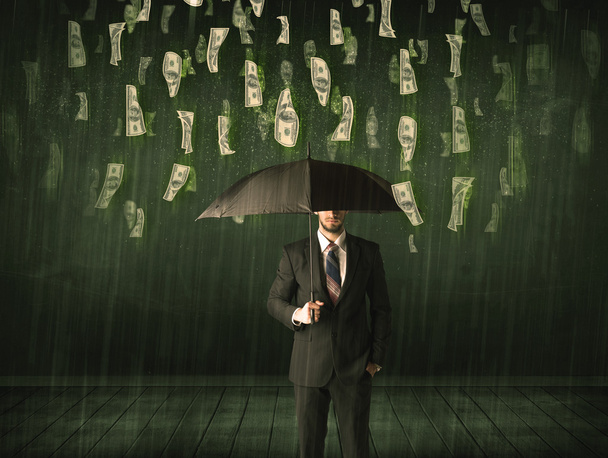Businessman standing with umbrella in dollar bill rain concept - Foto, afbeelding