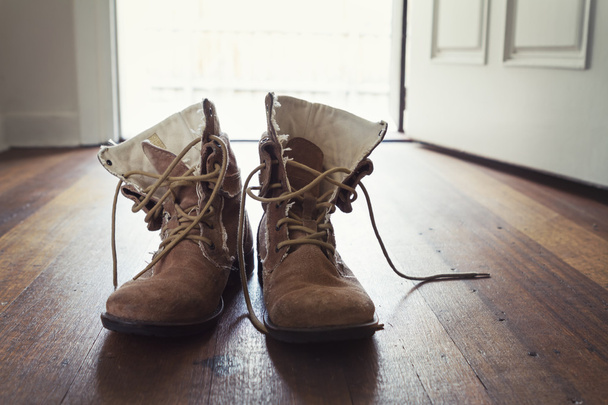 Par de botas de couro usadas masculinas na entrada da casa
 - Foto, Imagem