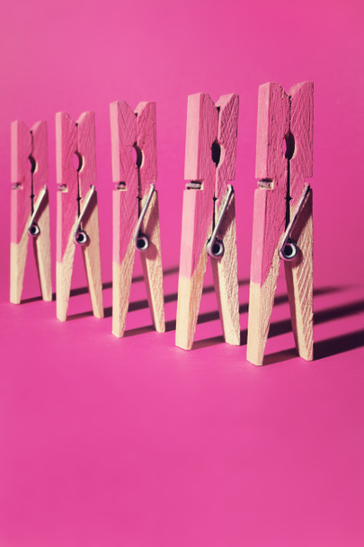 Row of pink painted clothes pegs on pink background - Photo, Image