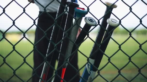 Бейсбольні біти притулившись паркан на бейсбол парк - Кадри, відео