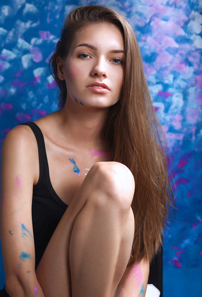 Young woman sitting near painting wall - Photo, Image