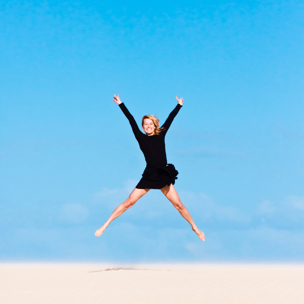 Mädchen springt in der Luft auf Sanddüne. - Foto, Bild