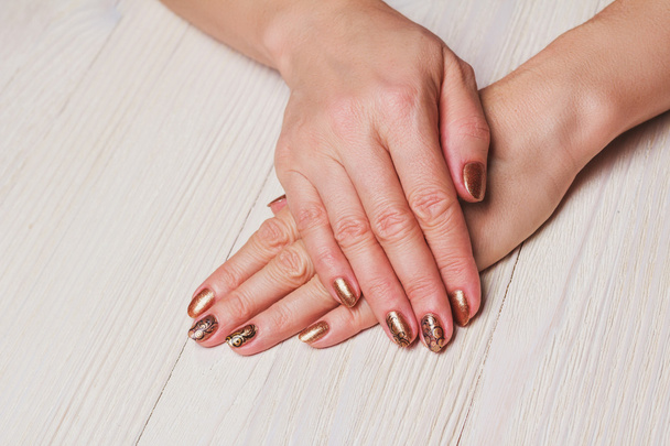 Arte de uñas de oro con remolinos pintados de negro
 - Foto, imagen