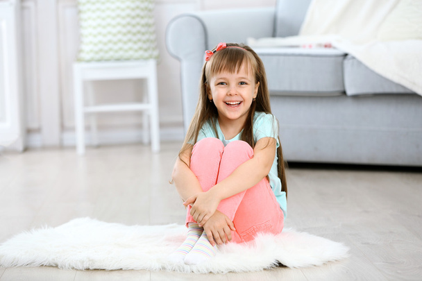 Маленькая милая девочка сидит на ковре
 - Фото, изображение